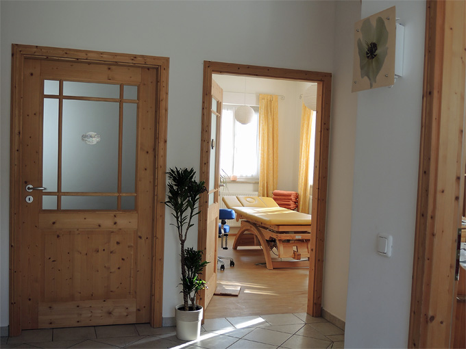 Foto vom Praxis-Eingang mit Blick in den Behandlungsraum mit der Behandlungsliege